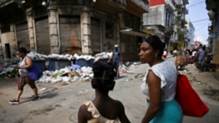 Personas caminan en La Habana entre montones de basura y comercios informales.